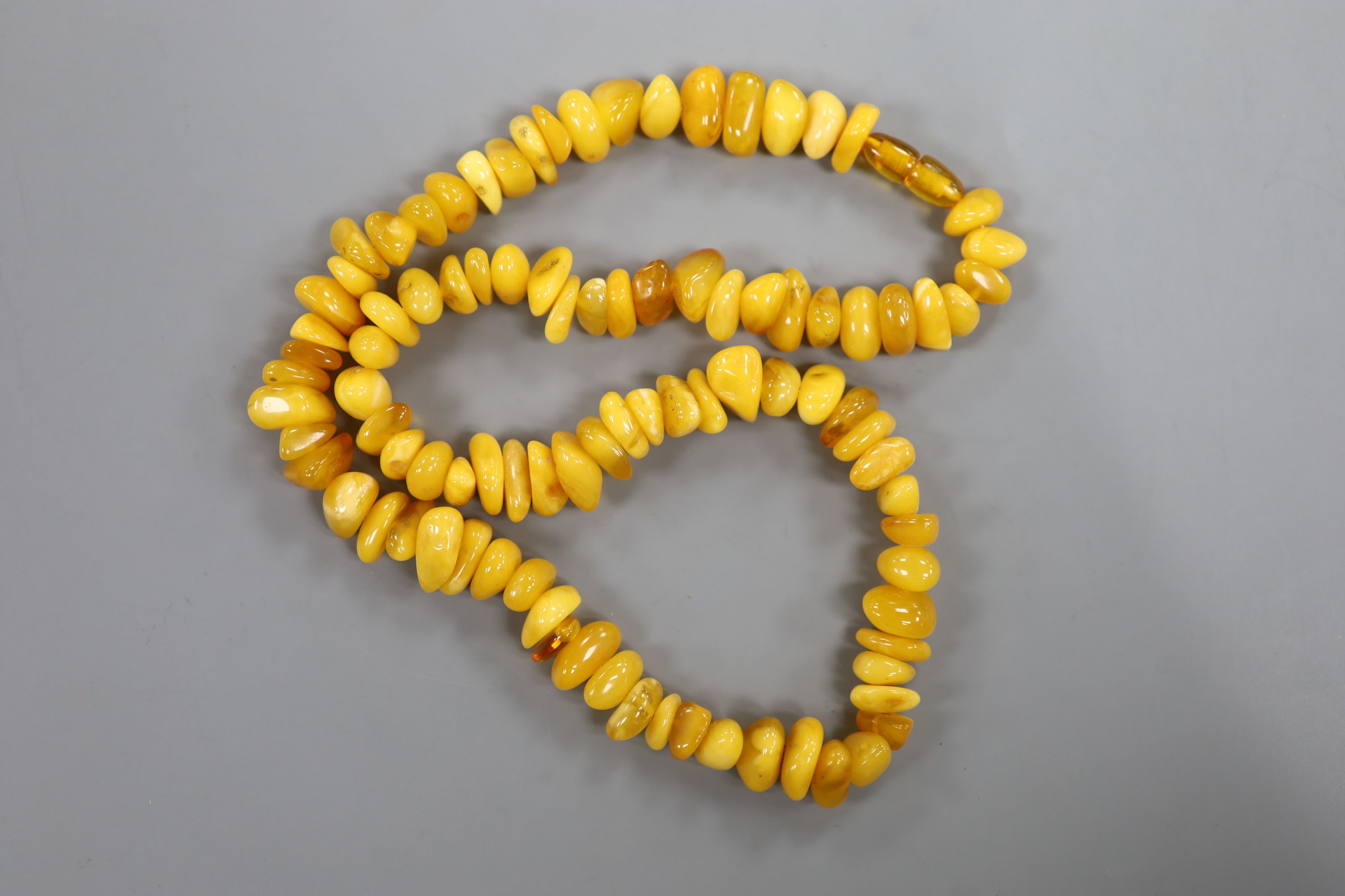 A single strand amber pebble necklace, approximately 66cm, gross weight 75 grams.